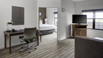 A hotel room with a bed, a desk with a chair, a television, and a window.