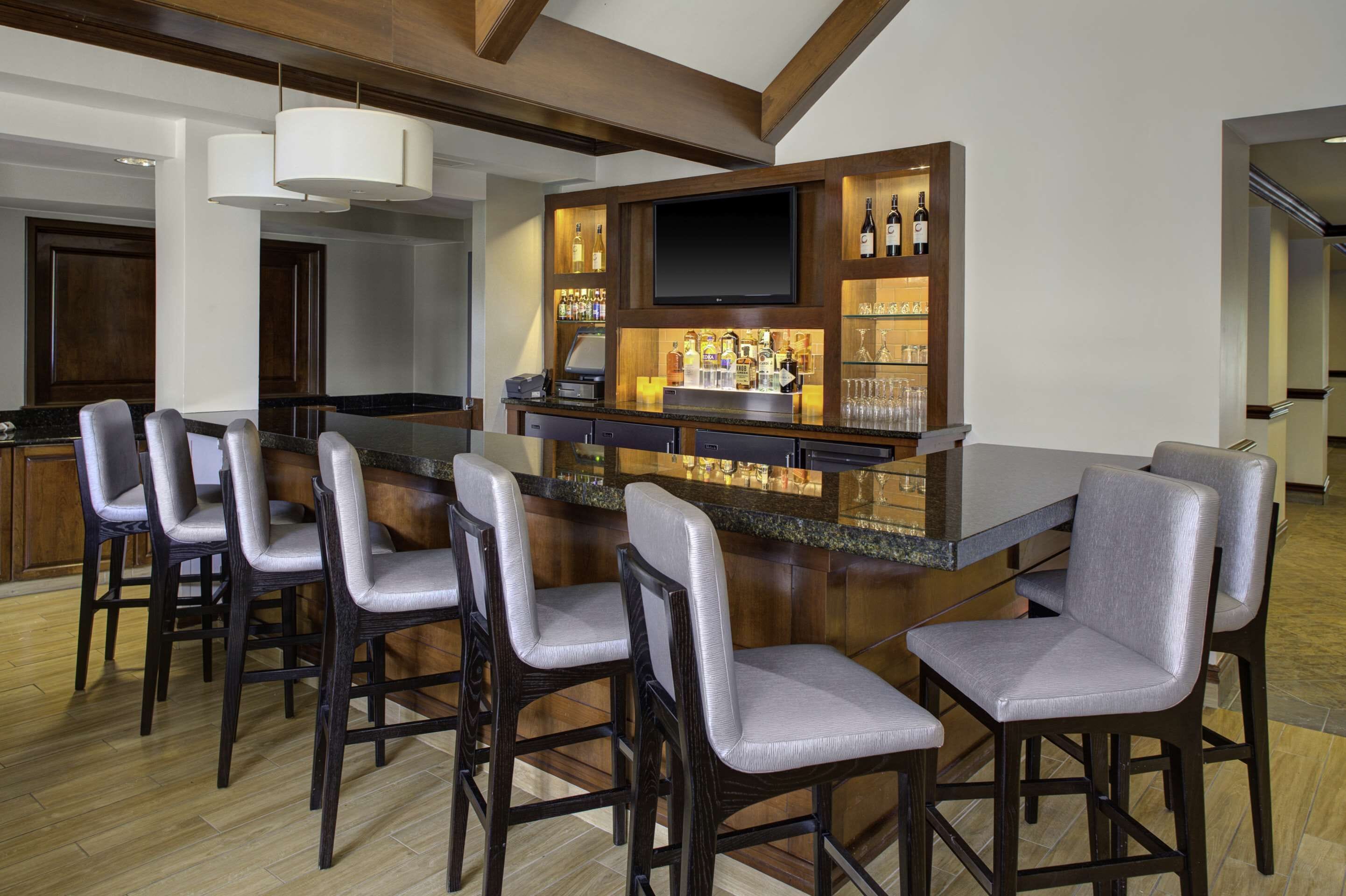 A modern kitchen with a bar area, bar stools, a flat-screen TV, and a wine display.