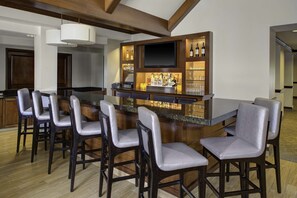 Une cuisine moderne dotée d’un coin bar, de tabourets de bar, d’un téléviseur à écran plat et d’un présentoir à vin.