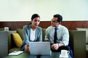 Two people sitting on a couch with a laptop and a notebook on a table. - HYATT house Parsippany-East (Parsippany)