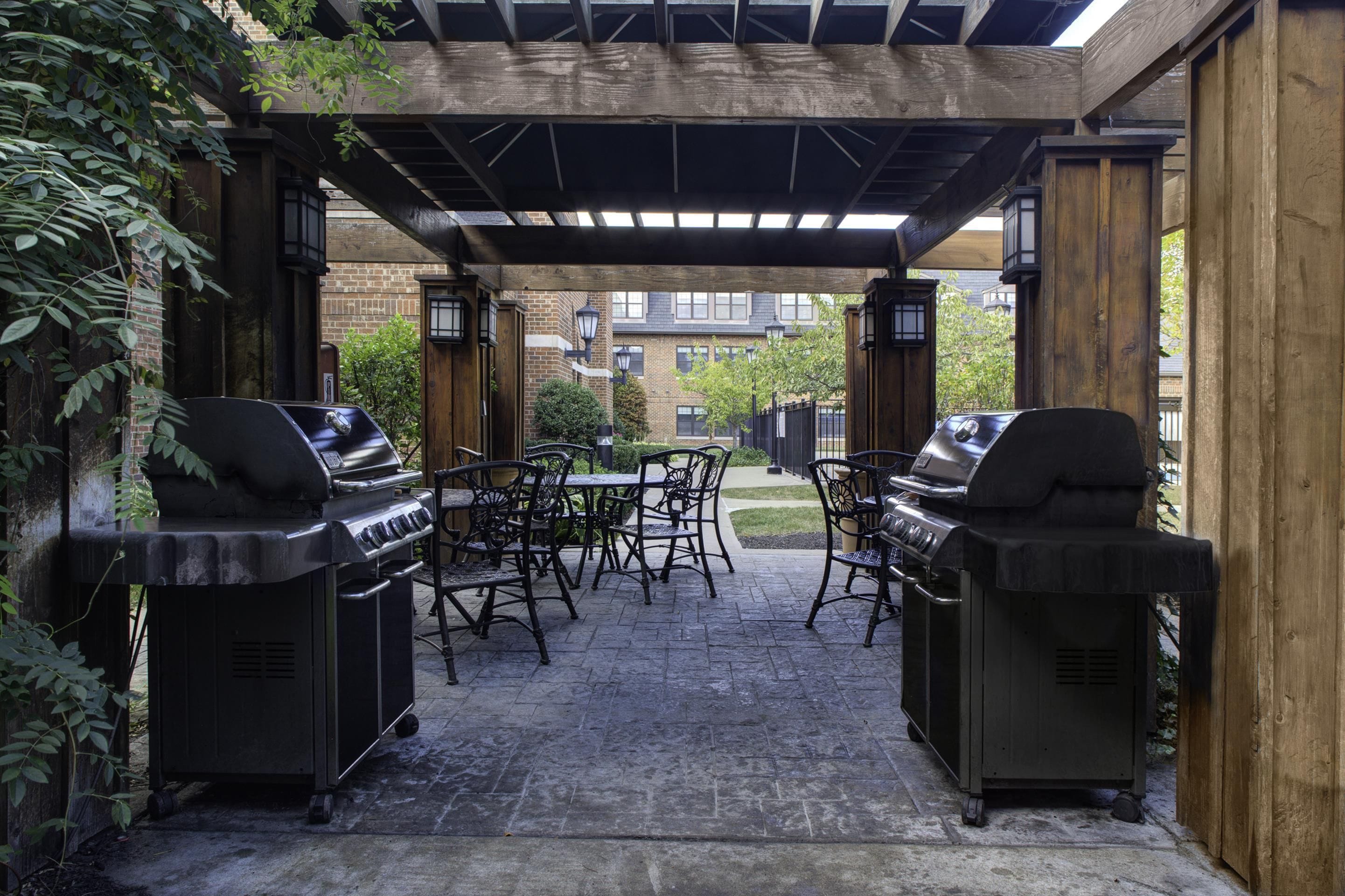 Eine Terrasse im Freien mit zwei Grillstationen, einem Tisch und Stühlen.