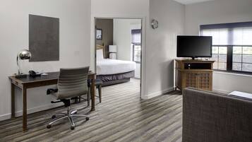 A hotel room with a bed, desk, chair, television, and a view of the outdoors through a window.