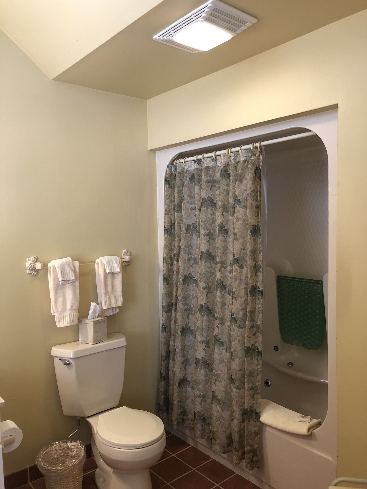 A bathroom with a toilet, a shower curtain, and a bathtub.