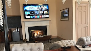 A hotel room with a TV displaying 'World of Dance', a fireplace, a bed, and a seating area with a remote control. - Chambery Inn (Lee)