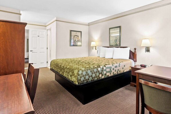 Quarto de hotel com cama, escrivaninha, cadeira e porta.