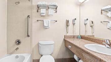 A modern bathroom with a bathtub, toilet, and sink. There are towels and a hairdryer on the wall.