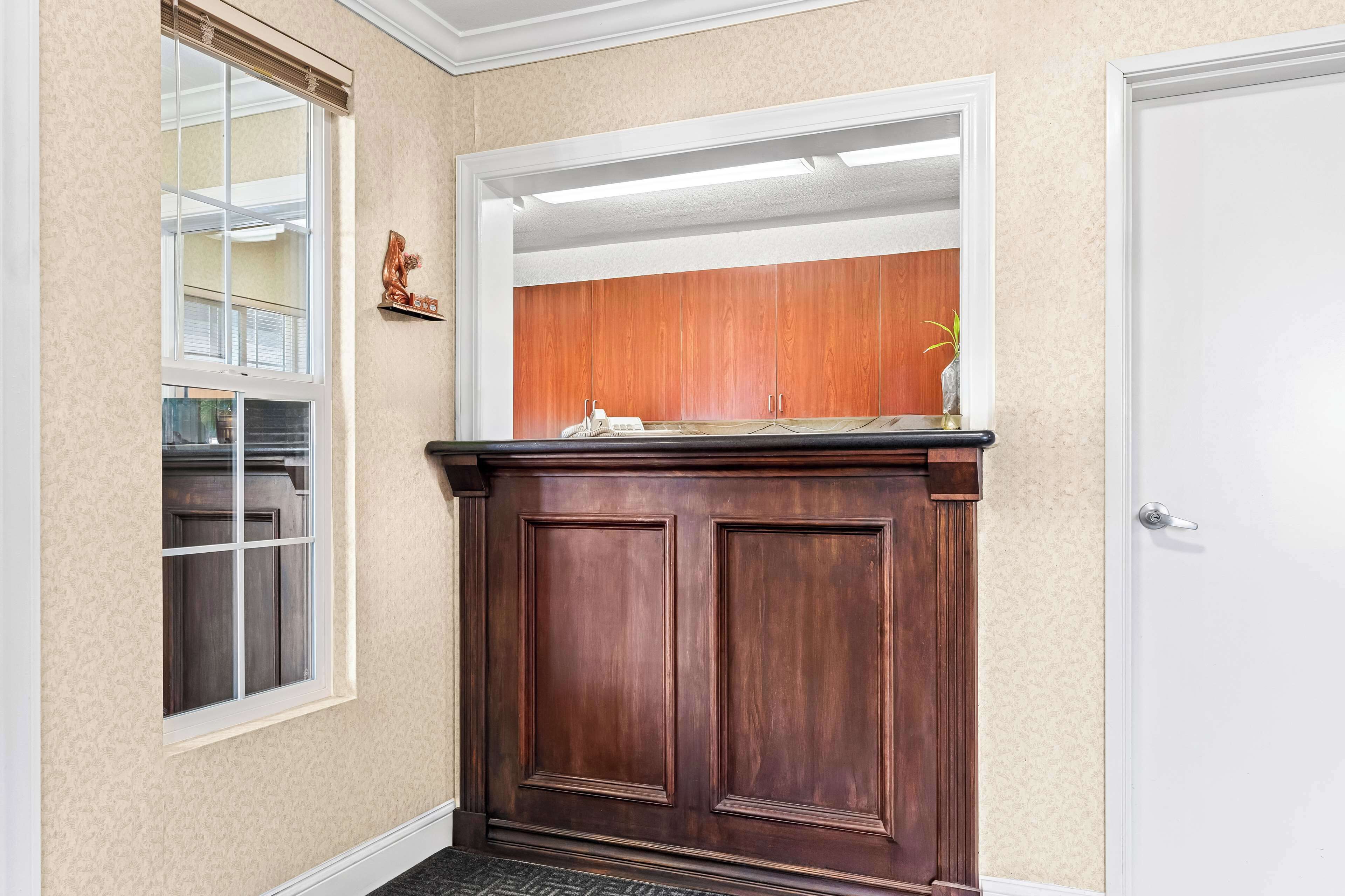 A hallway with a wooden door, a mirror, and a window with blinds.