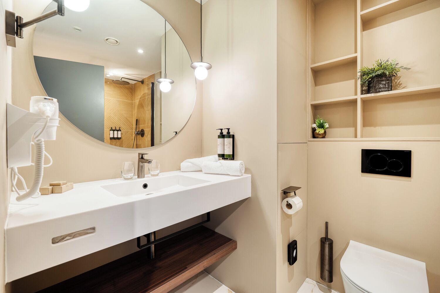 Un baño moderno con un espejo grande, dos lavamanos, un inodoro y una zona de ducha.