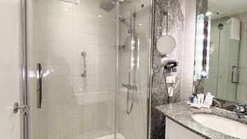 A modern bathroom with a glass-enclosed shower, a marble countertop, and a large mirror.