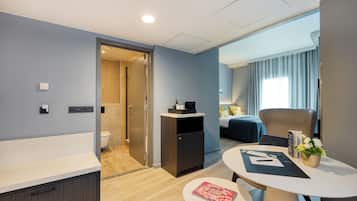 Una habitación de hotel moderna con baño, comedor y dormitorio.