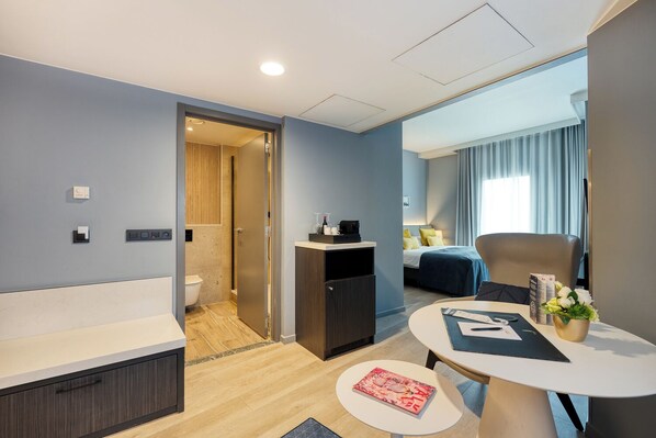 A modern hotel room with a bathroom, a dining area, and a bedroom.