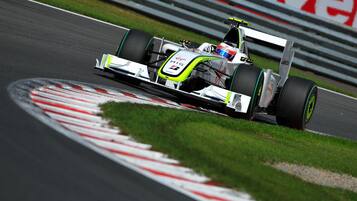 Een raceauto op een baan met afscherming en gras.