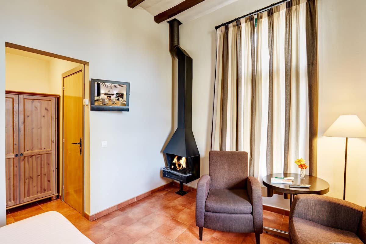 Een gezellige woonkamer met een open haard, een houten garderobe en een eethoek met een tafel en stoelen.