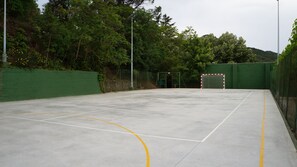 An outdoor tennis court with a goal post, surrounded by green fencing and trees. - Hotel Rural y Apartamentos Villa Engracia (L'Espluga de Francoli)