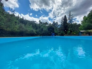 A clear blue pool surrounded by dense forest. - Hotel Rural y Apartamentos Villa Engracia (L'Espluga de Francoli)