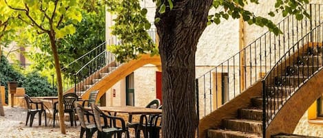 Un patio con mobiliario exterior, una escalera y un árbol.