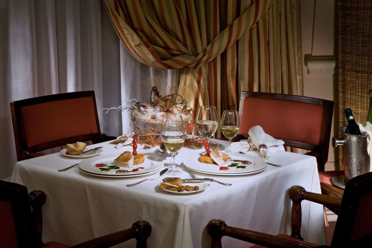 A dining table set with plates, cutlery, and glasses, surrounded by chairs.