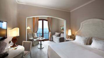 Una camera d'hotel con un letto, una scrivania con una sedia, una televisione e un balcone con tende.