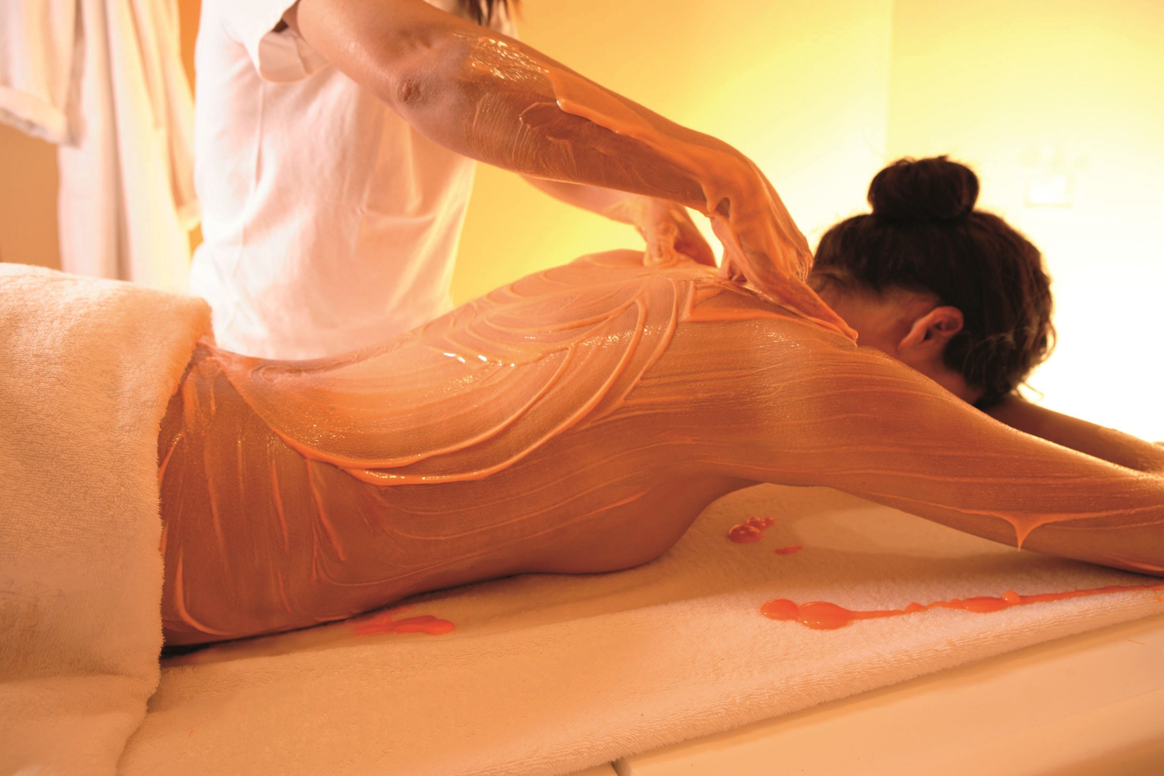 A person receiving a massage on a massage table in a room with a plain wall and a window.