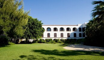 Un edificio bianco con diversi archi e un giardino antistante.