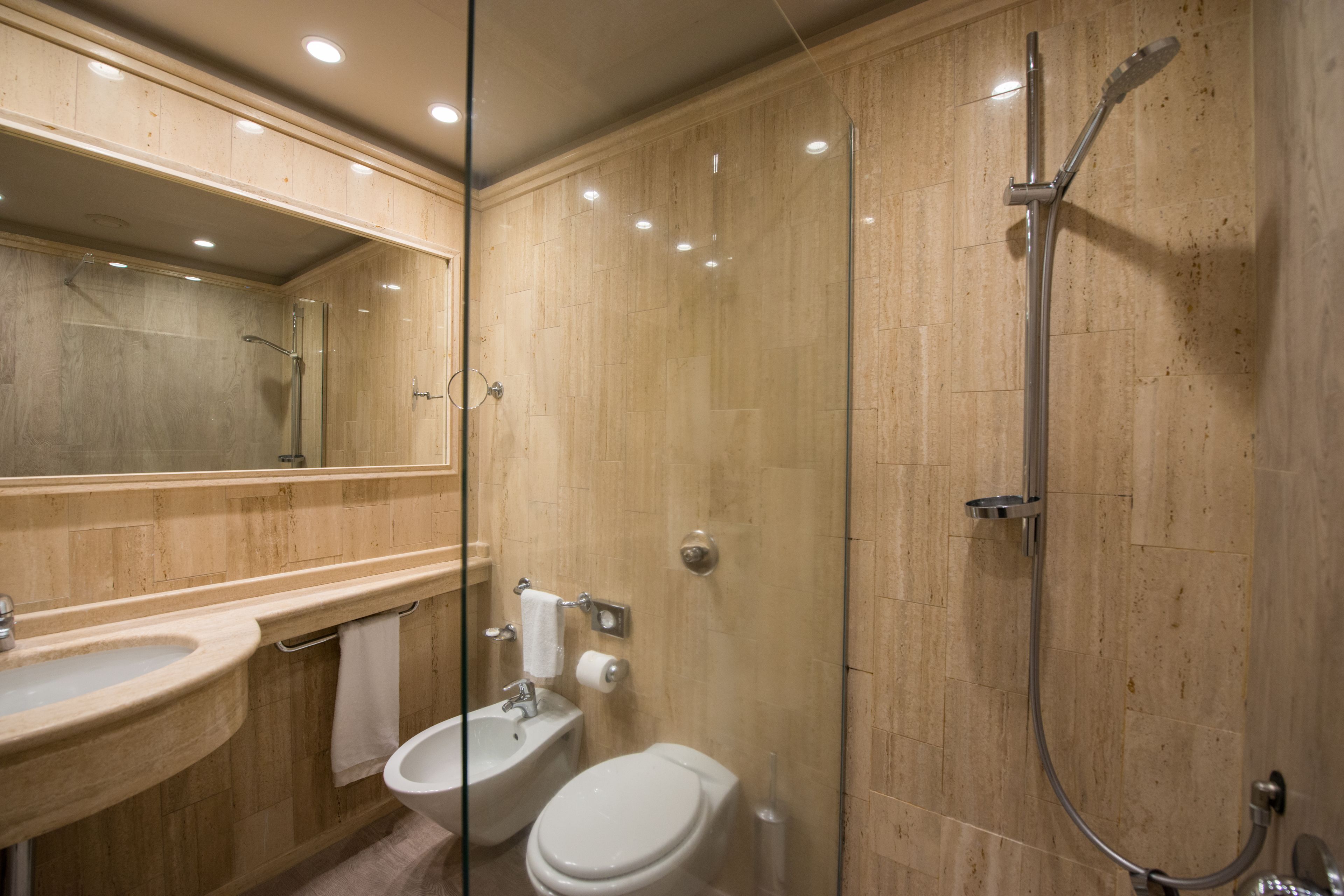 Un baño moderno con ducha de vidrio, lavamanos e inodoro.