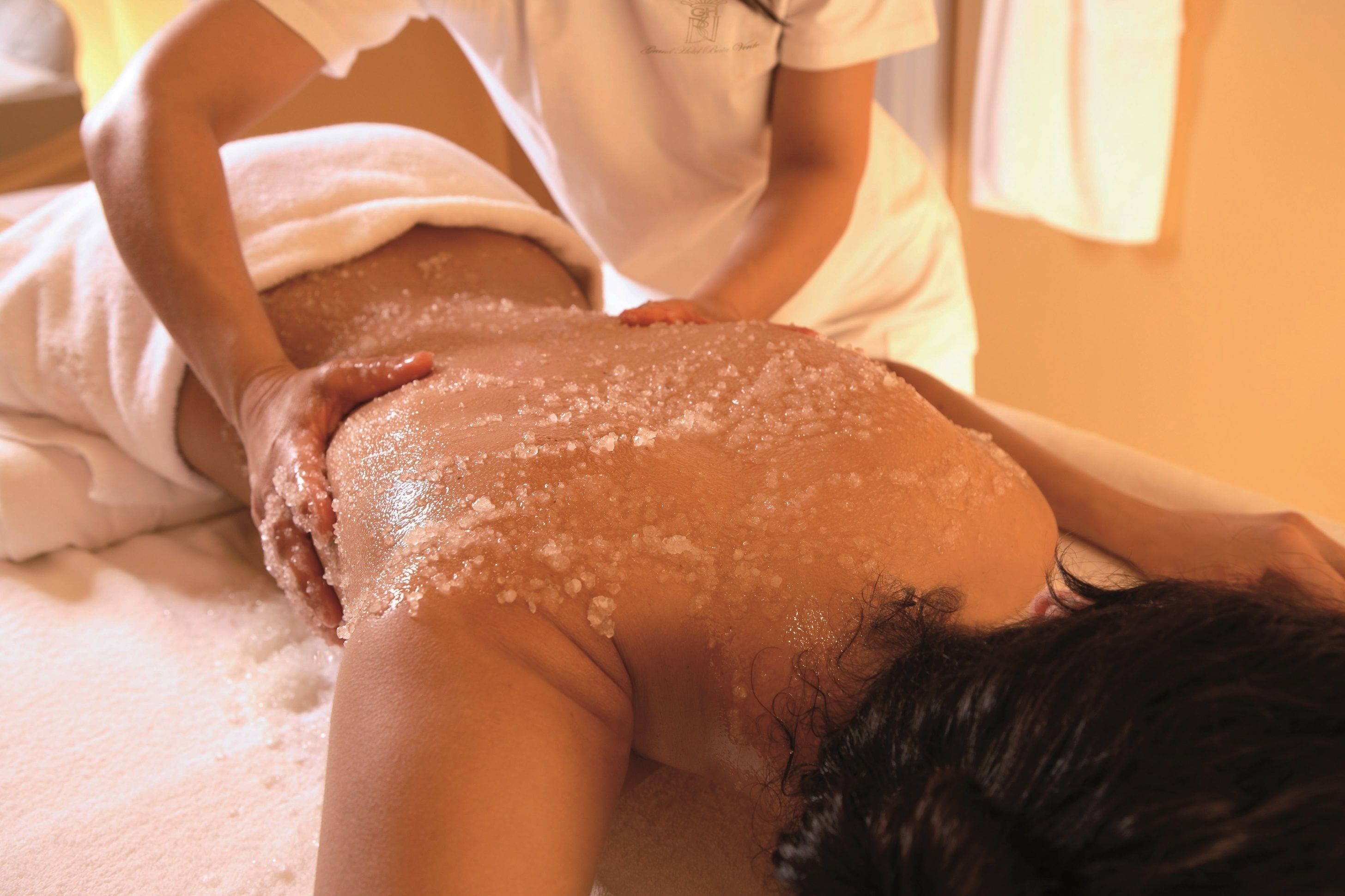 A person receiving a back massage with salt on their back.