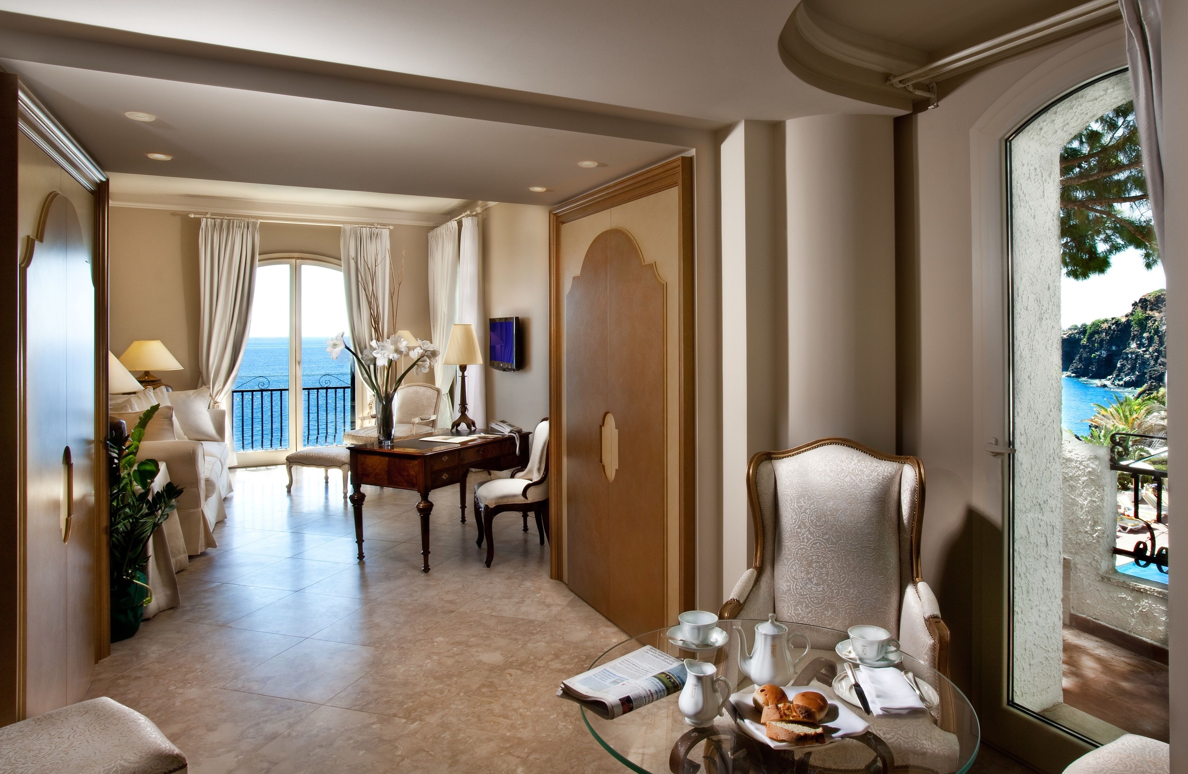Habitación de hotel con balcón, zona de comedor y vistas al mar.