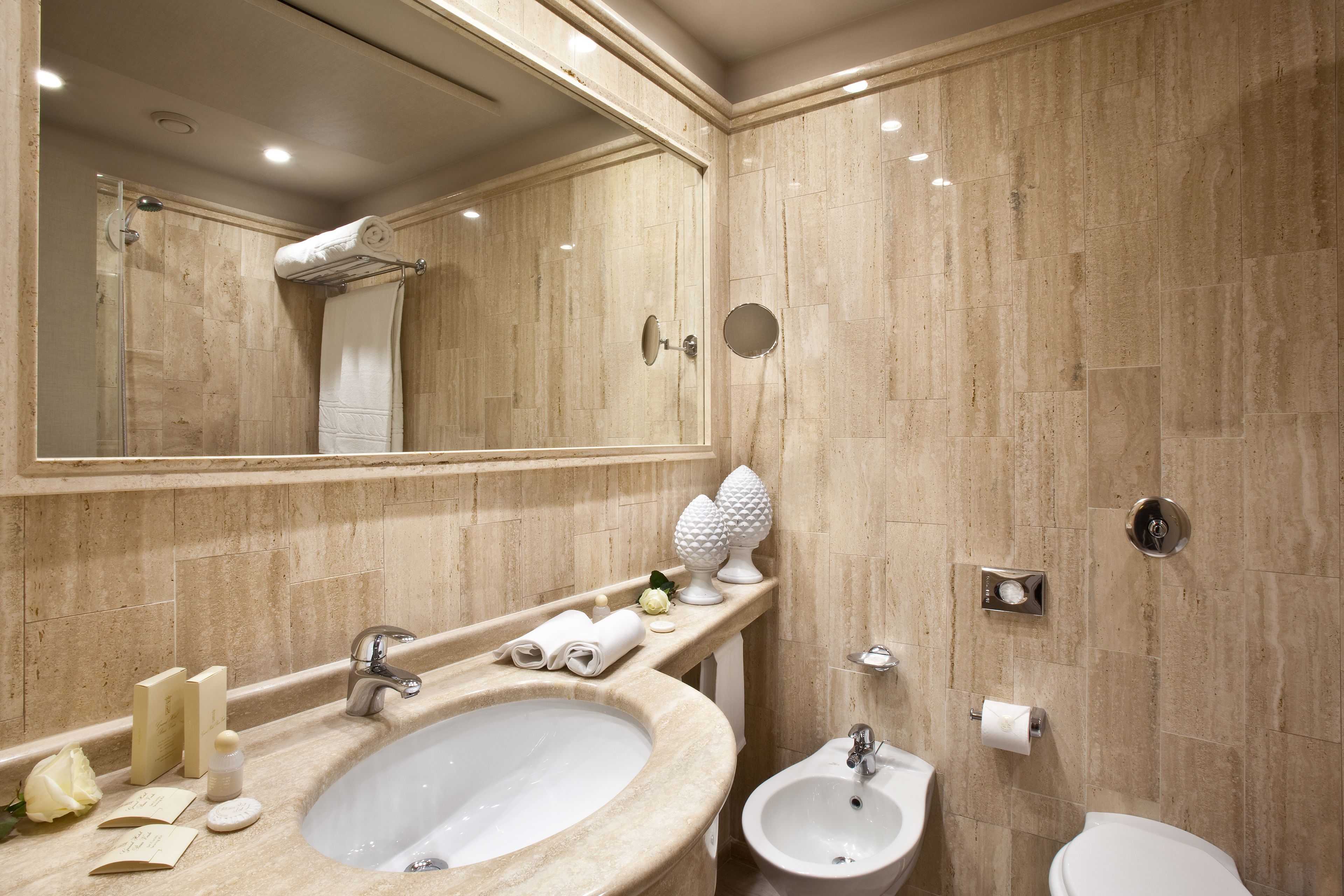 Un baño con lavamanos, bidé, inodoro y un espejo grande.