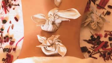 En person får en massage på ryggen, och tygblommor är fastknutna längs ryggraden.