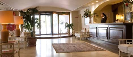 A spacious lobby with a reception desk, seating area, and large windows.