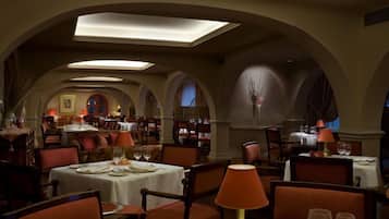 Un restaurant doté de nombreuses tables et chaises, de plafonds en arc de cercle et d’un éclairage chaleureux.