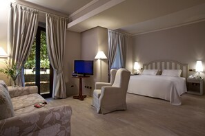 A hotel room with a bed, two armchairs, a TV, and a small table. - Grand Hotel Baia Verde (Aci Castello)