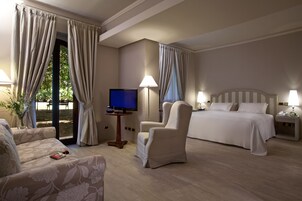 Una camera d'albergo con un letto, due poltrone, una TV e un tavolino.