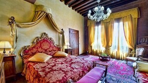 Una habitación con una cama grande y elaborada, un candelabro y un techo clásico de madera.