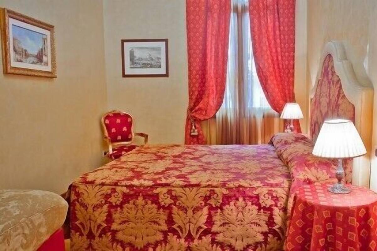 Ein Hotelzimmer mit einem großen Bett, einem Sessel, einem Tisch mit Lampe und zwei gerahmten Bildern an der Wand.