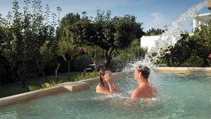 A swimming pool with two people in the water, surrounded by greenery and a water fountain. - Hotel Al Mulino - Mediterranean Garden Retreat in AnaCapri (Anacapri)