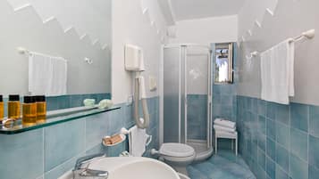 Casa de banho com chuveiro de cabine de vidro, lavatório branco e sanita.