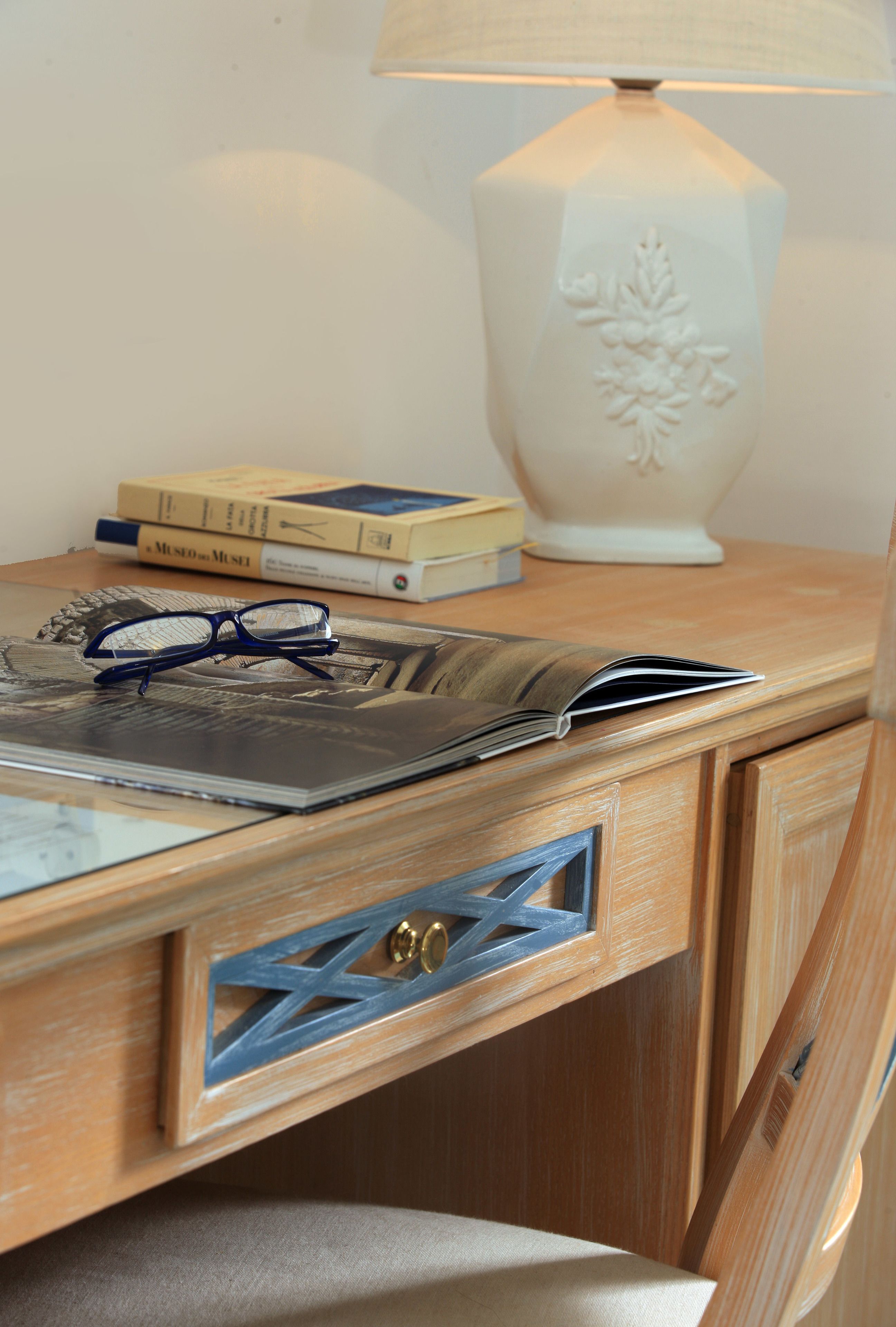 Ein Holztisch mit einer Lampe, Büchern, einer Brille und einer Zeitschrift.