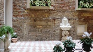 Un patio con suelo a cuadros, paredes de piedra y plantas en macetas.
