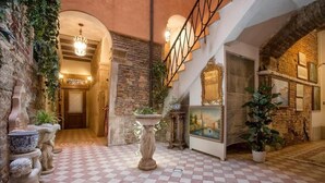 Un suelo a cuadros, paredes de piedra, una escalera y un candelabro.