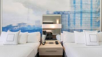 A hotel room with two beds, a desk, and a mirror.