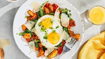 Un plato de comida con huevos, patatas y verduras.