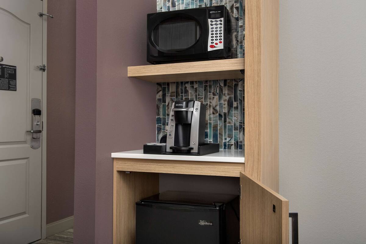 Une petite cuisine équipée d’un four à micro-ondes, d’une machine à café et d’un réfrigérateur.