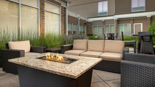 Un patio exterior con un brasero, muebles de mimbre y vistas del exterior del edificio.