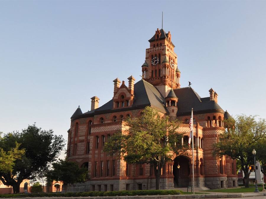A large, historic building with a prominent clock tower, arched windows, and a symmetrical facade.
