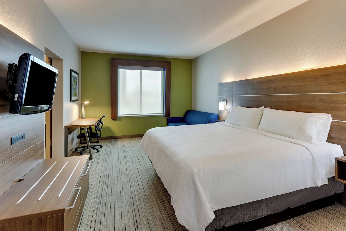 Una habitación de hotel con una cama grande, un escritorio, una silla, un televisor y una ventana.