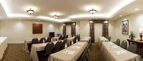 A conference room with long tables, chairs, and a carpeted floor.