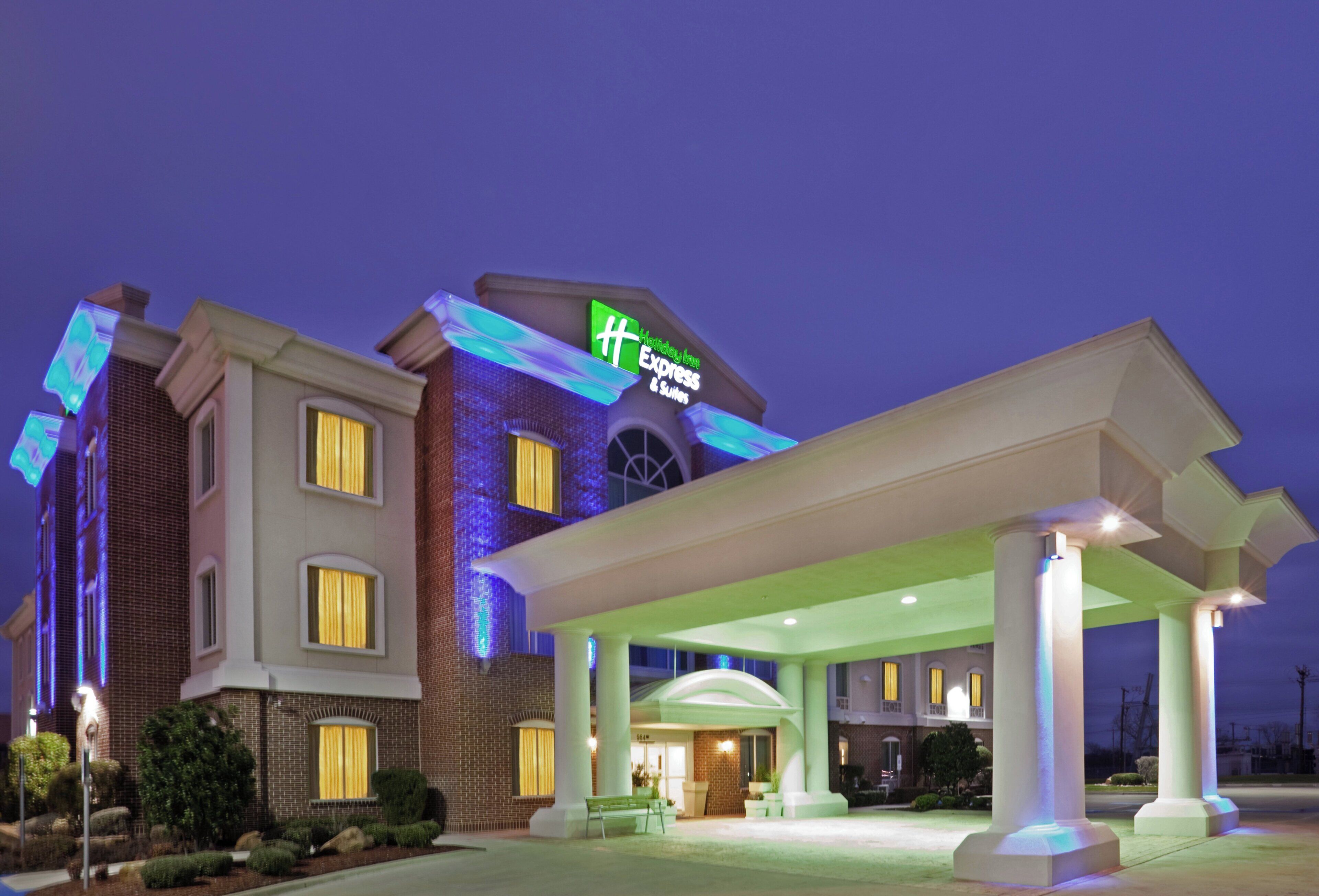 A hotel with a prominent sign, a covered entrance, and a brick facade.
