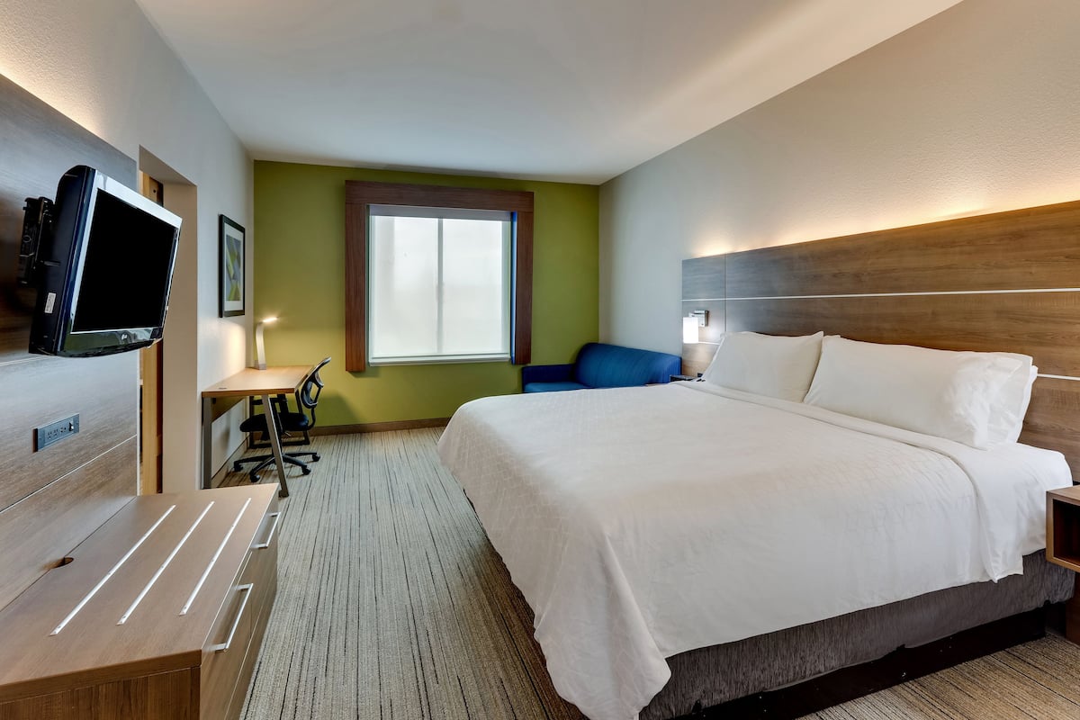 Una habitación de hotel con una cama grande, un escritorio, una silla, un televisor y una ventana.