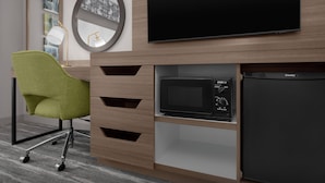 A modern hotel room with a flat-screen TV, a microwave, and a refrigerator.